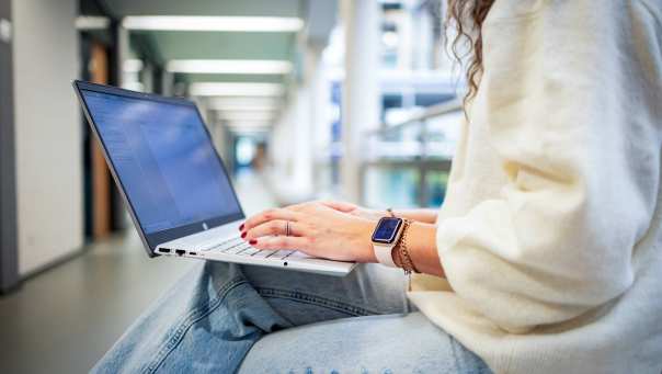 Student van de bachelor Commercile Economie deeltijd, duaal in gang met laptop.