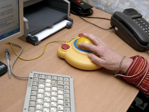 een ernstig spastische patiente werkt achter haar computer met behulp van aangepast toetsenbord en muis