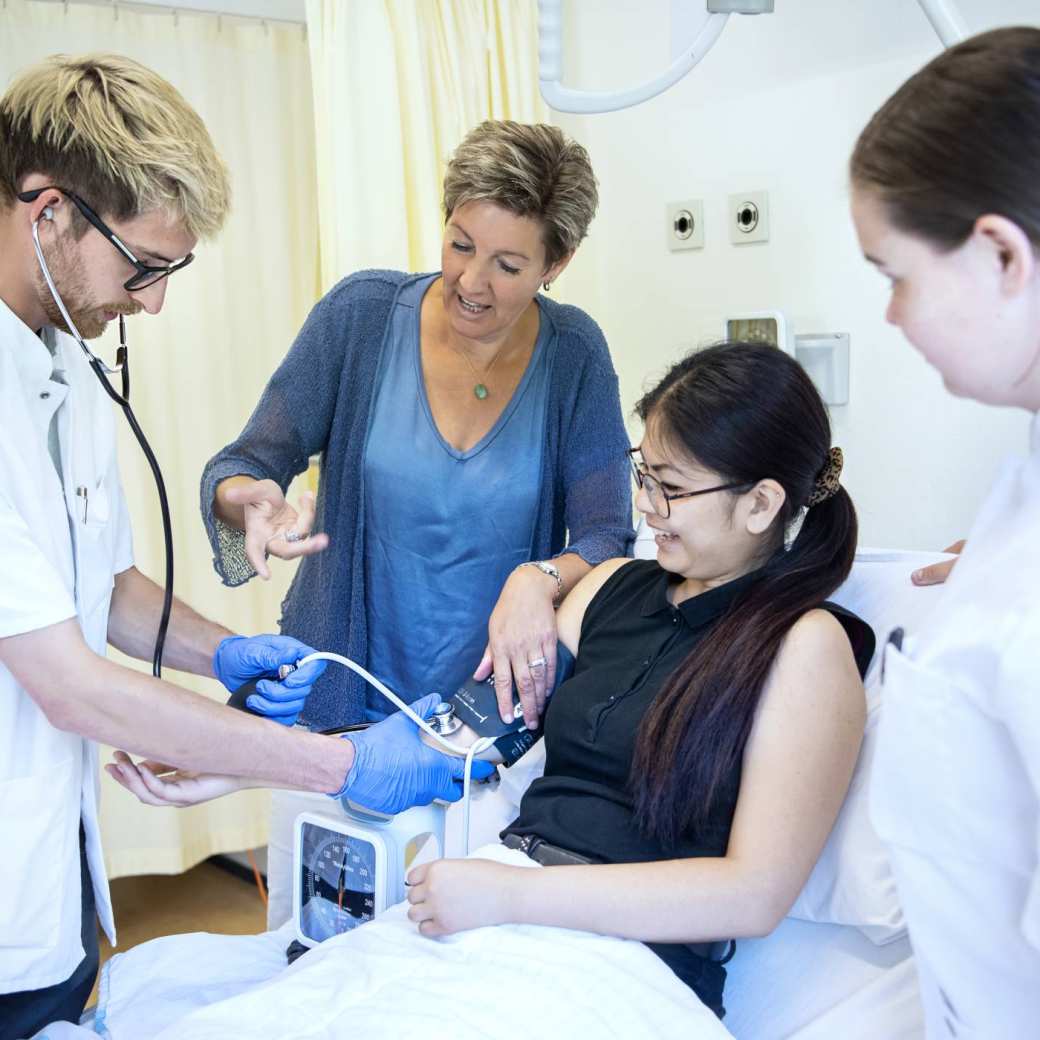 Twee studenten behandelen patiënt in bed BMH