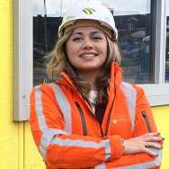 Portret foto van Farnaz Amini met helm voor een gele bouwkeet.