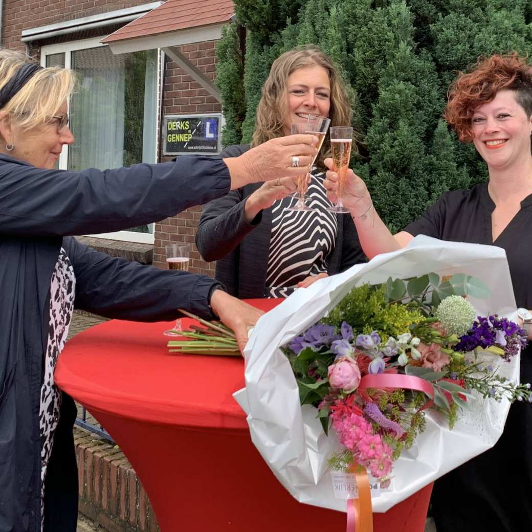 Drie vrouwen proosten op Niki Reijnen en er ligt een bos bloemen op tafel