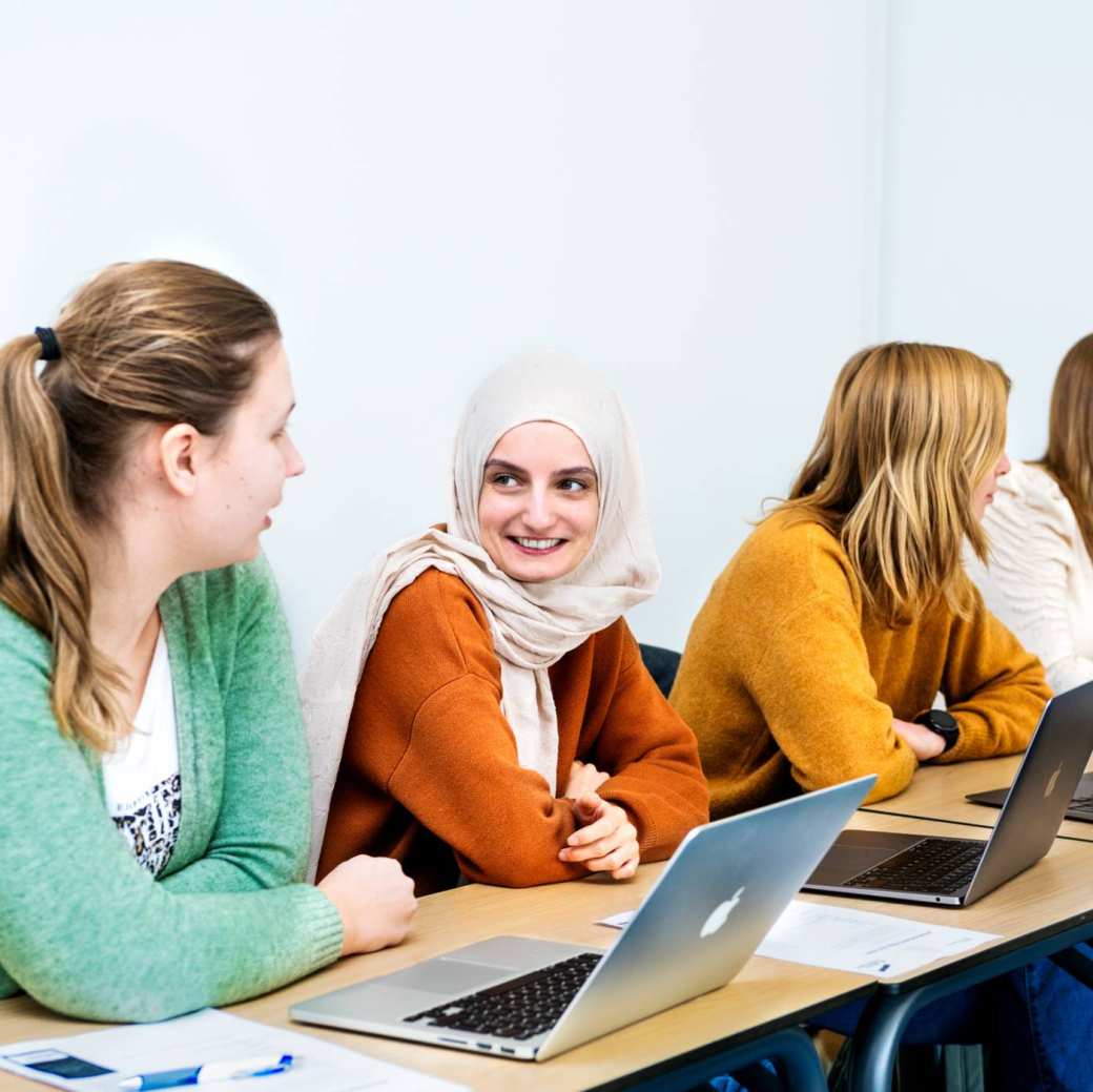 Studenten met laptop aop tafel tijdens een les.