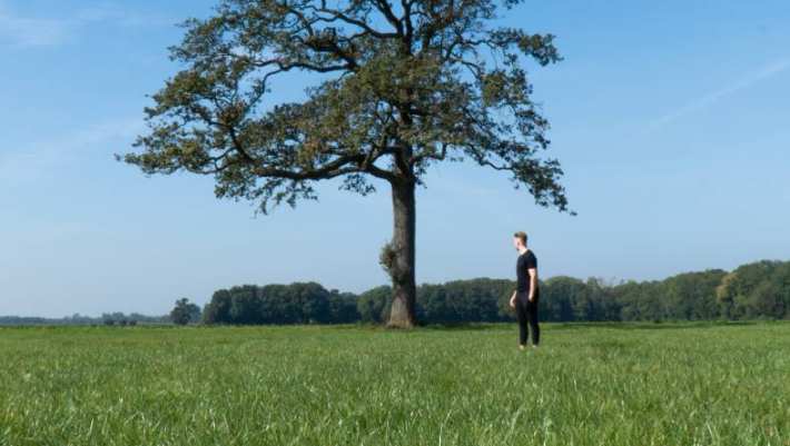 Foto van Finance & Control-student Mylan ter Vrugt in een grasveld voor een boom.