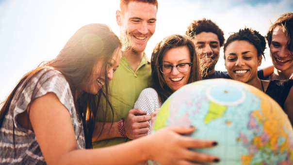 Een groep internationale studenten houdt een wereldbol vast die het internationale karakter van de studie International Social Work voorstelt.