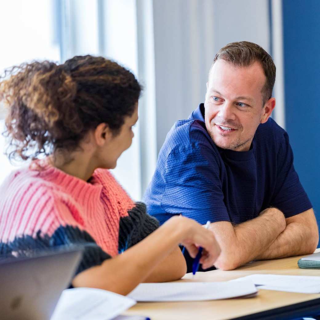 2 cursisten overleggen lachend met elkaar op de HAN-campus.