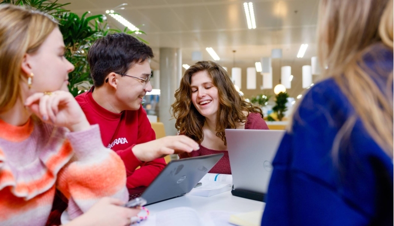 Studenten zitten lachend achter de laptop