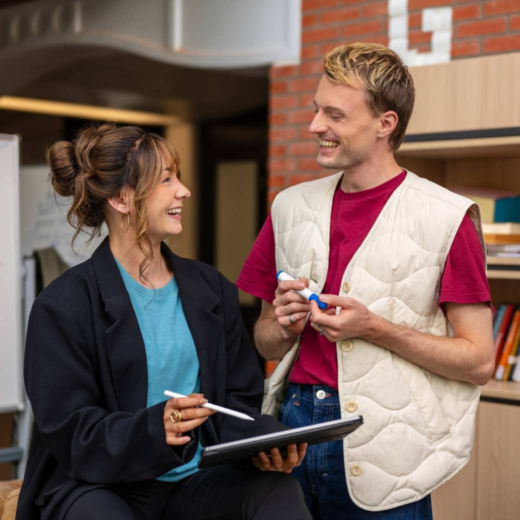 Twee bezoekers op de Open Avond lachen met elkaar.