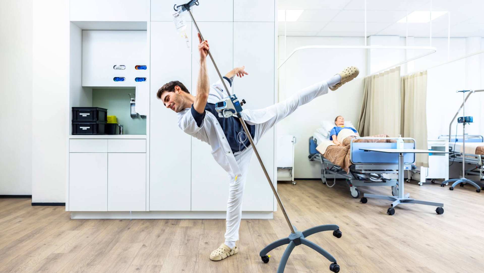 Verpleegkundige danst in ziekenhuis met infuuskarretje.