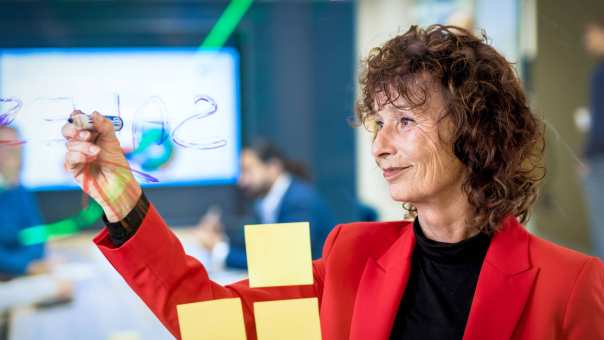 Docent van de master Business Sales plakt post-its op glazen wand.