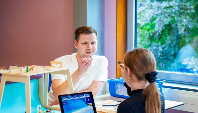 Coördinator Digitale Geletterdheid is in gesprek met een basisschoolleerling bij een laptop.
