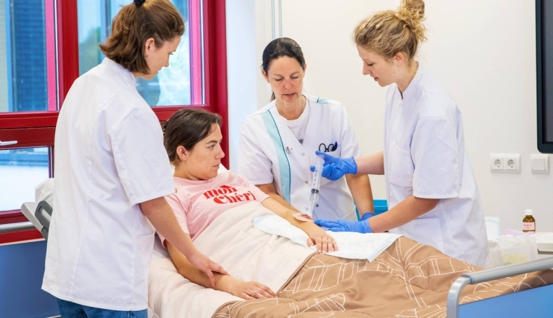 Studenten en docent Verpleegkunde bezig tijdens praktijkles