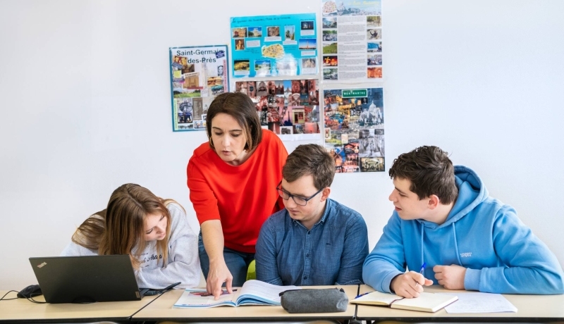 Docent wijst in boek en studenten kijken toe