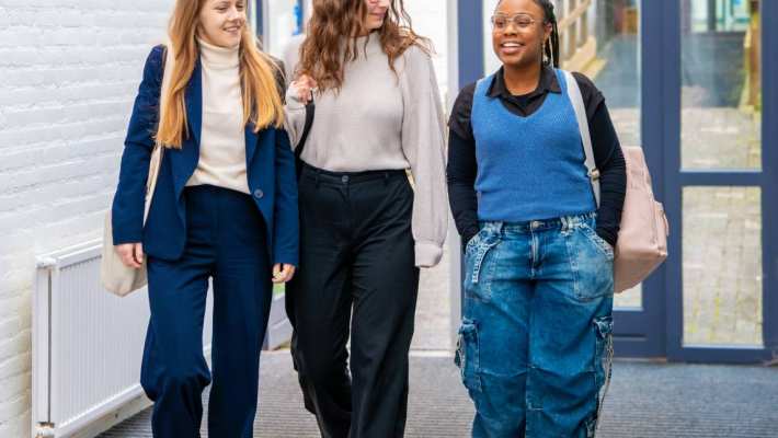 3 vrouwen lopen richting de camera, lachen met elkaar.