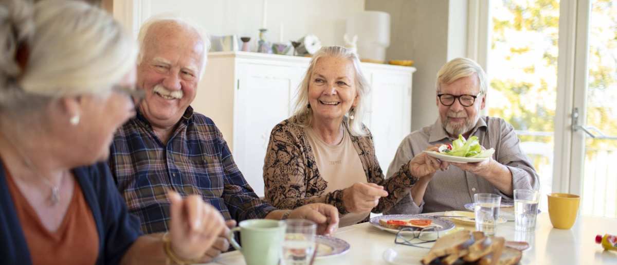 Groep ouderen aan tafel tijdens het ontbijt in een verpleeghuis