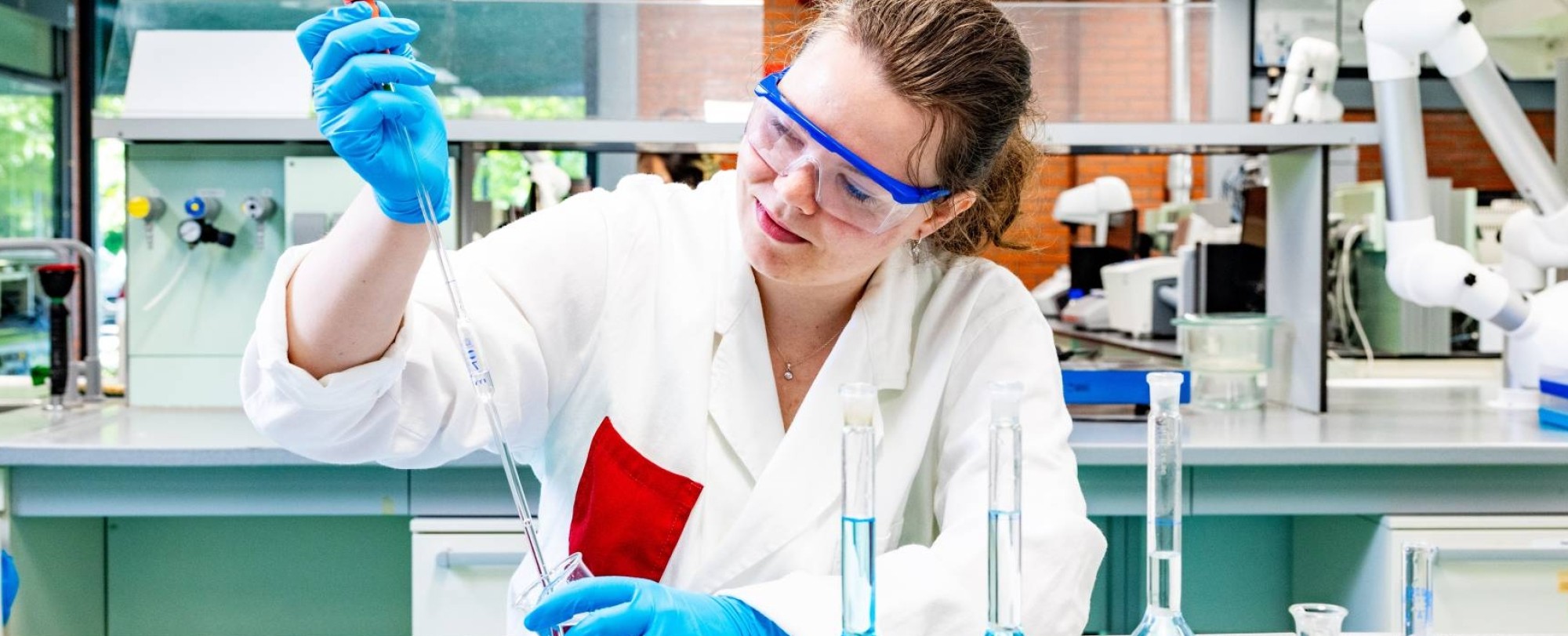 student pipetteert met een volumepipet in een chemie lab