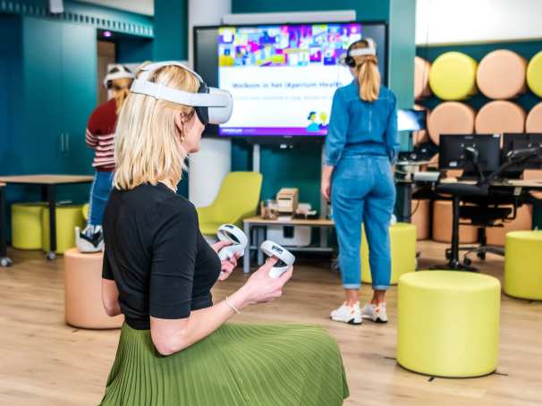 Foto van iXperium Health, waar 2 studenten en een docent een VR-bril op hebben.