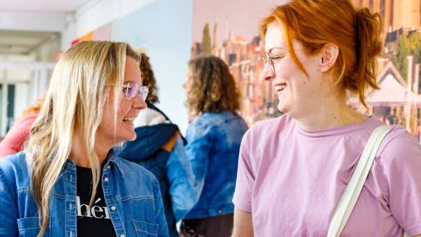 Vrouw laat iets zien op haar mobiel tijdens de cursus acute pijn service. Andere studenten moeten lachen.