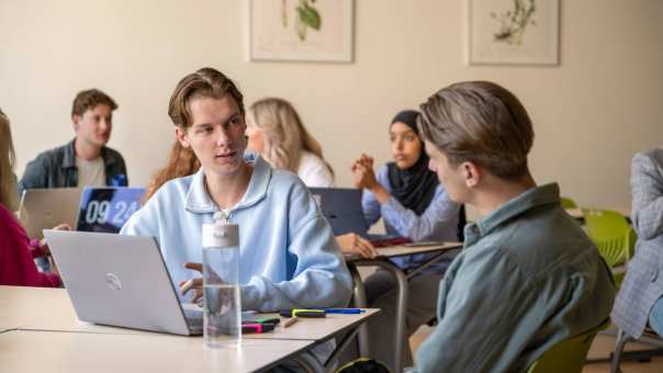 Twee jongens aan tafel in een klas overleggen samen. 