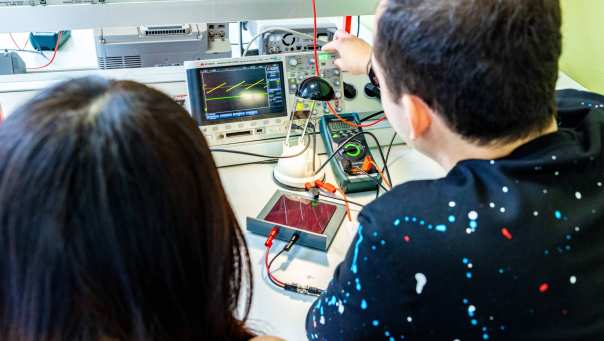 Twee studenten elektrotechniek doen een experiment met een zonnepaneel.