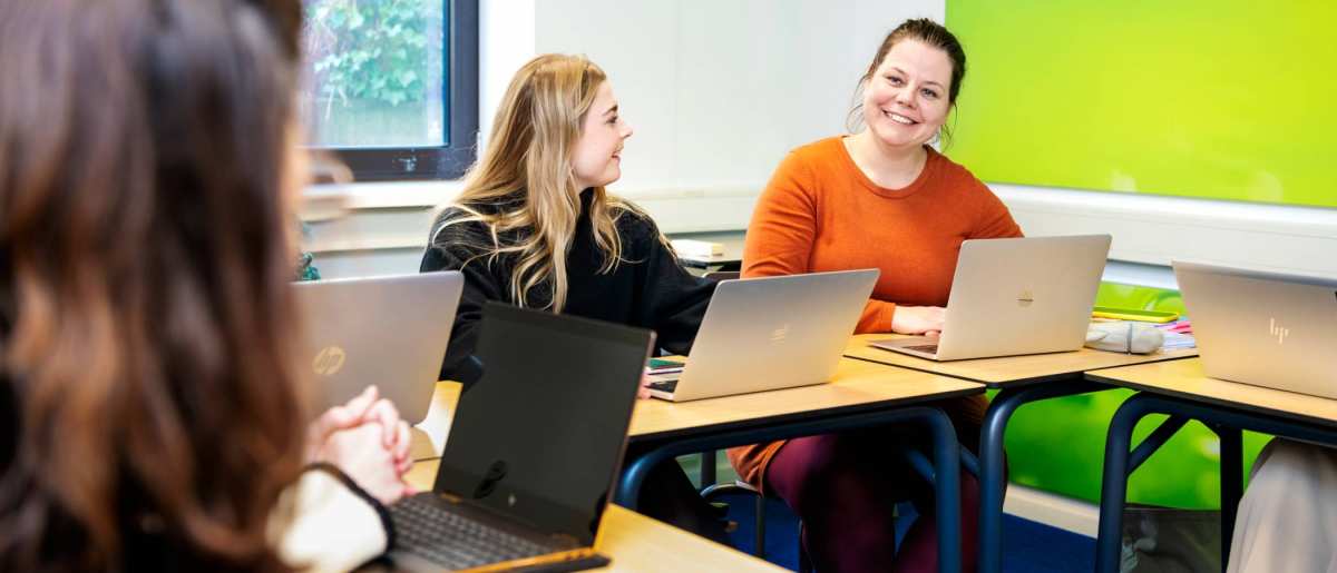 Student kijkt lachend medestudenten aan