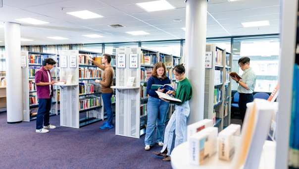 International students browsing through study books in the library on the Arnhem campus of HAN University of Applied Sciences.