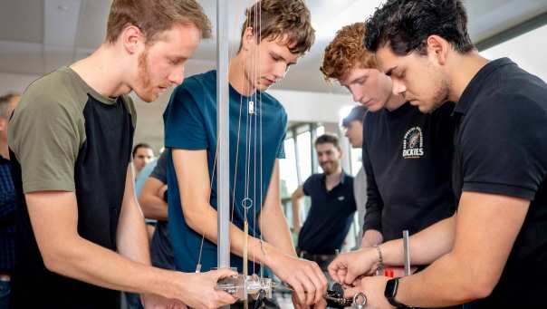 Vier studenten werktuigbouwkunde doen tests met een katrol en gewichten.