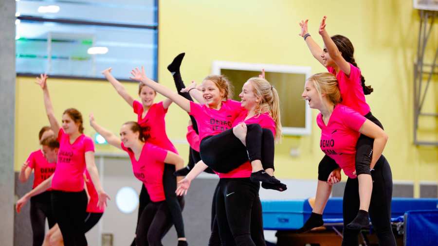 Meisjes en studenten dansen en sporten in het demoteam tijdens de open dag