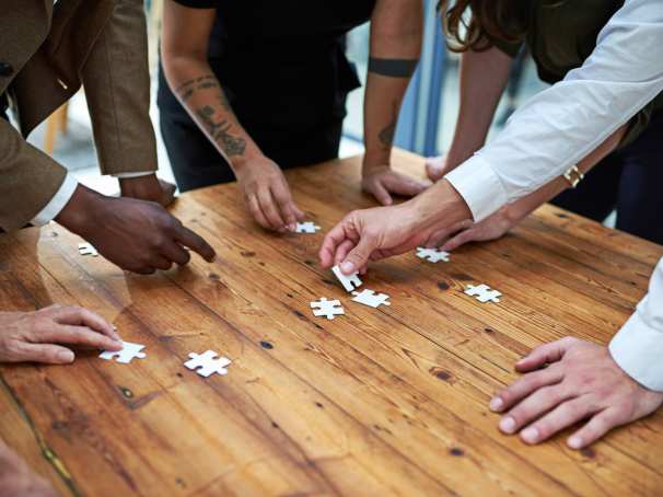 Op een vierkante houten tafel samen een puzzel leggen. Puzzelstukjes, samenwerken, seece