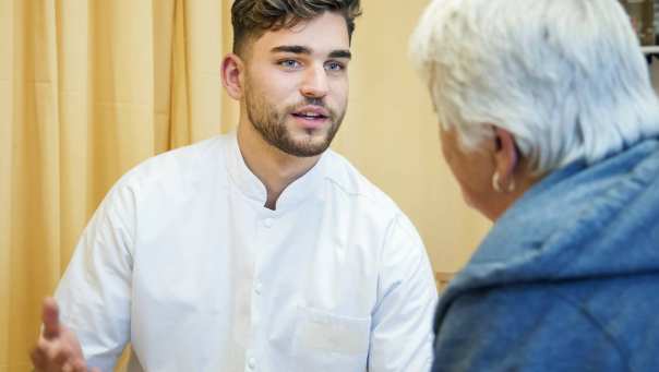 Fysiotherapeut in gesprek met een cliënt in het ziekenhuis