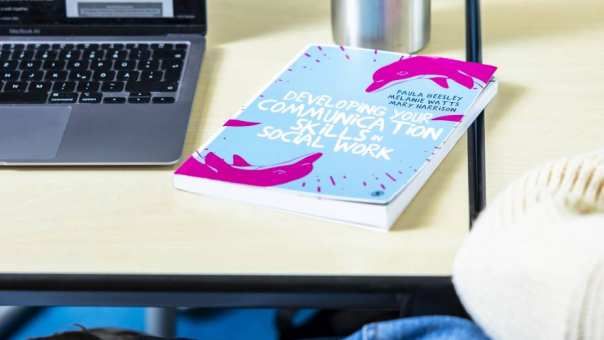 International Social Work. laptop en boek op tafel tijdens college