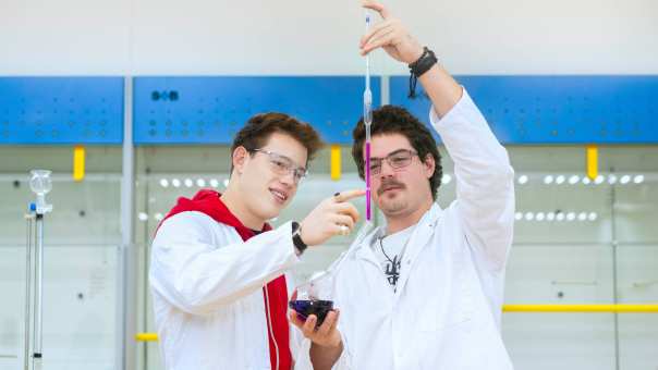 Twee studenten voegen vloeistoffen samen.
