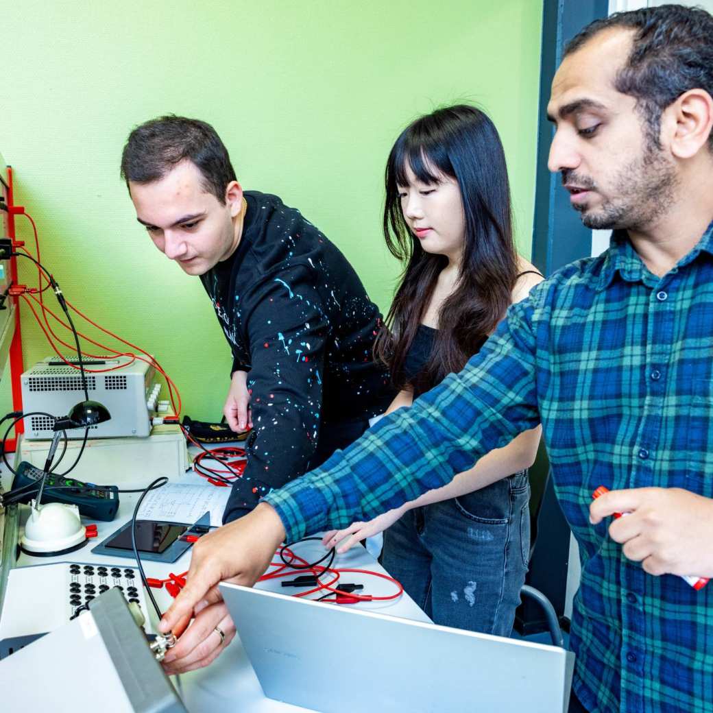 Een elektrotechniekdocent geeft uitleg over een zonnepaneel aan studenten.