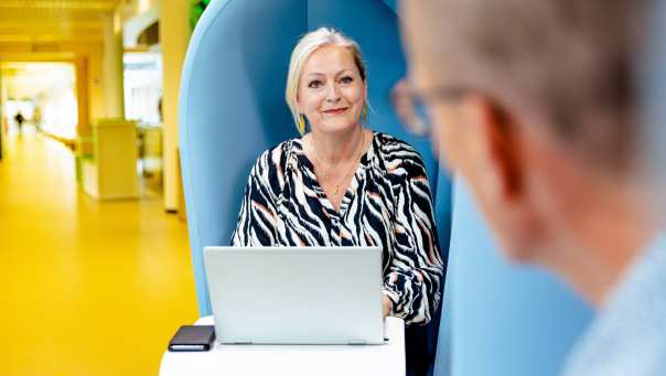 Vrouw van middelbare leeftijd in een blauwe stoel met laptop
