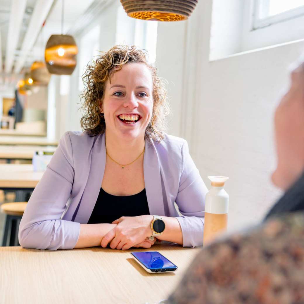 Vrouw in gesprek, moet lachen. Tijdens de cursus acute pijn service, in de kantine.