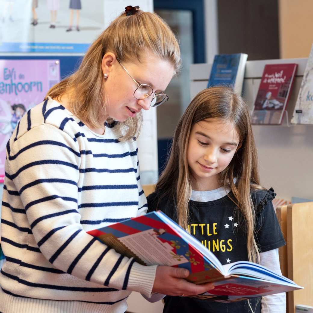 Docent leest samen met leerling een boek