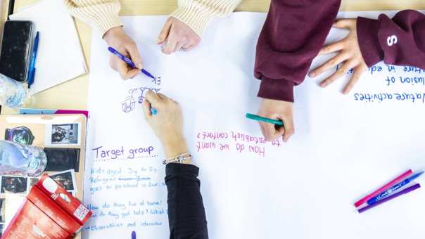 Studenten International Social Work tekenen op een papier tijdens college.