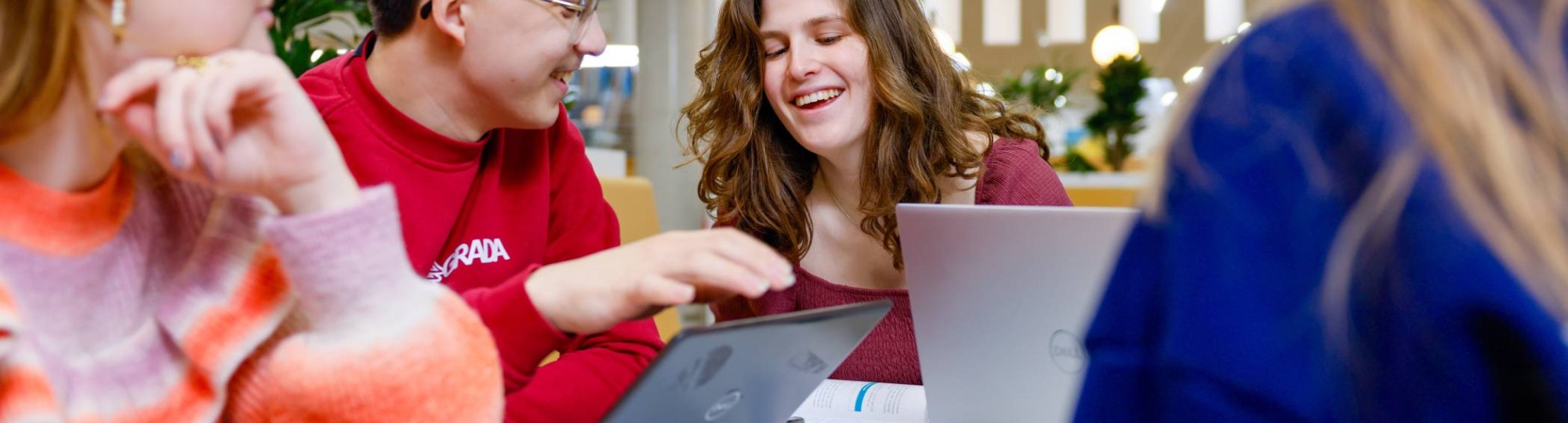 Studenten zitten lachend achter de laptop