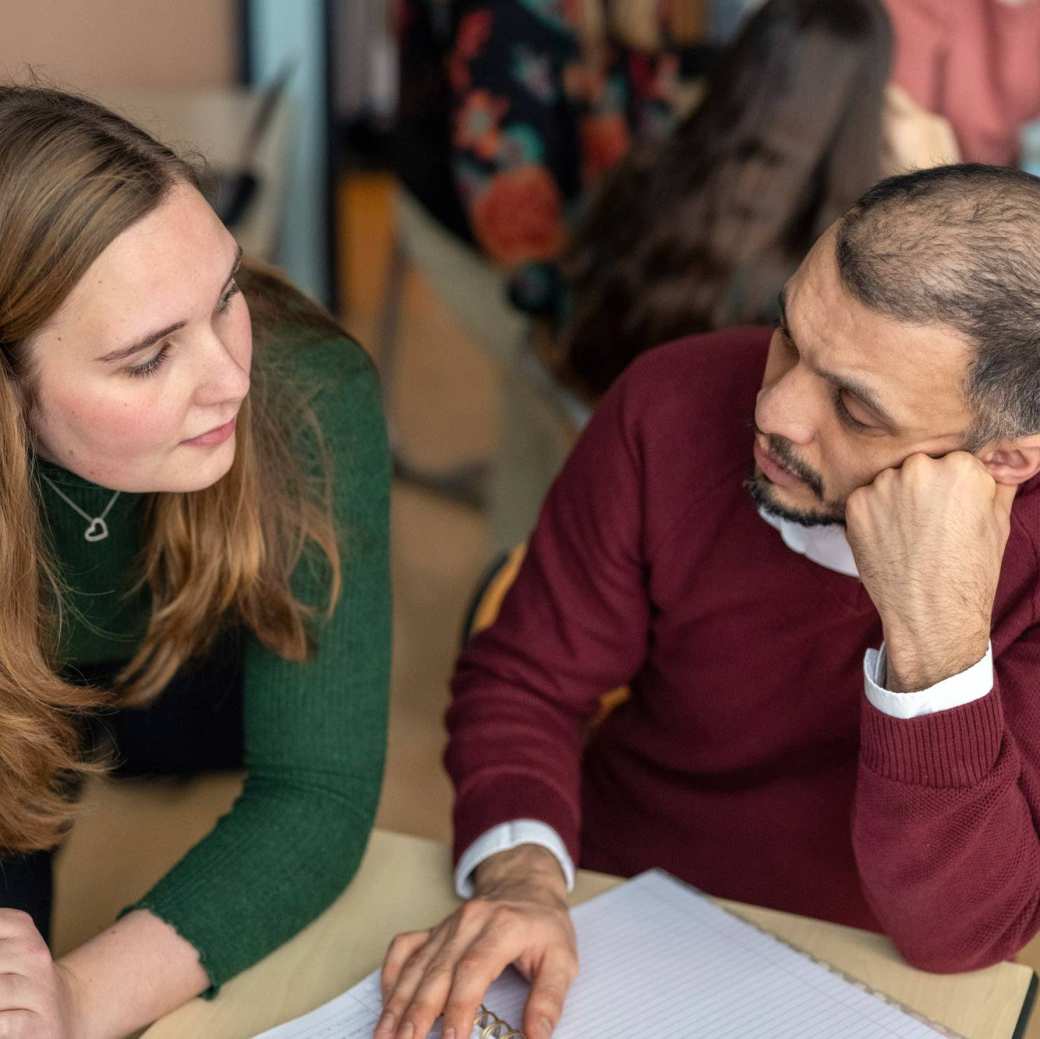 2 studenten kijken elkaar aan terwijl ze overleggen. 