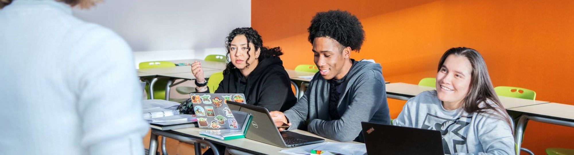 vier masterstudenten aan tafel moeten lachen en kijken elkaar aan.