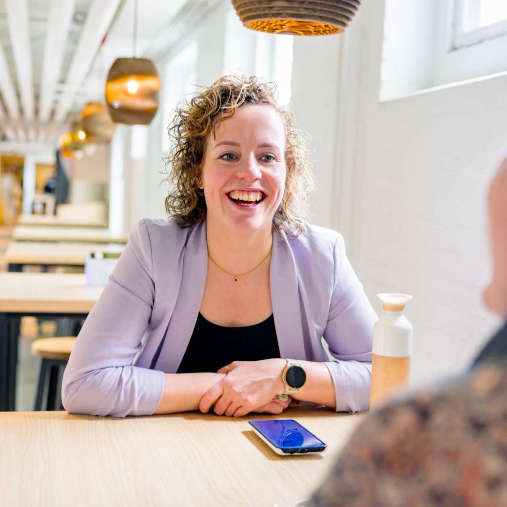 Vrouw in gesprek, moet lachen. Tijdens de cursus acute pijn service, in de kantine.