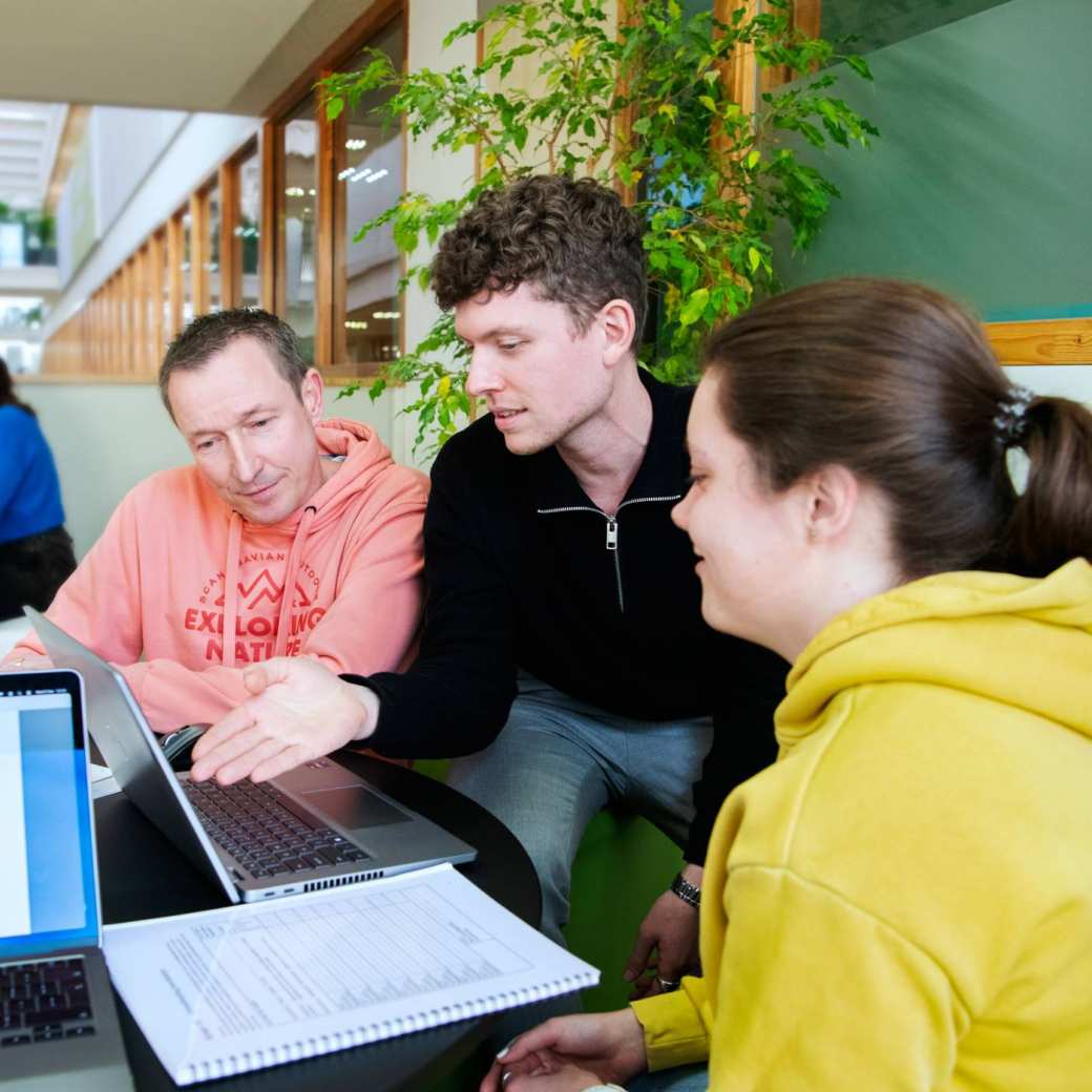 3 masterstudenten zitten bij elkaar en kijken aandachtig naar een laptopscherm