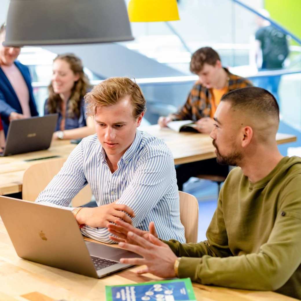 2 studenten in overleg bij een laptop over een storing.