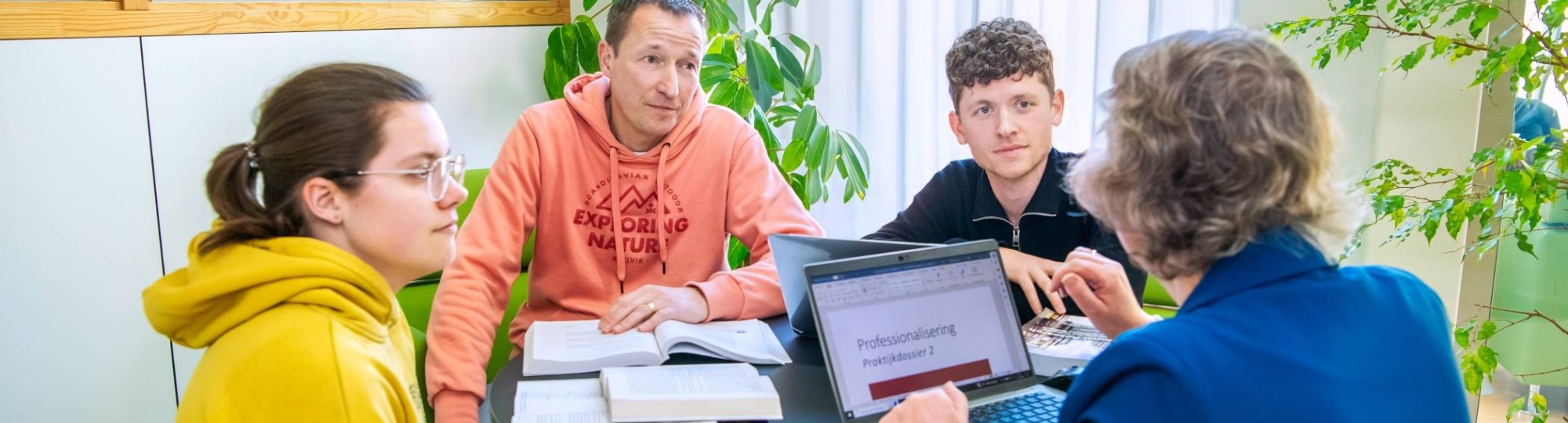 drie masterstudenten kijken naar een laptop