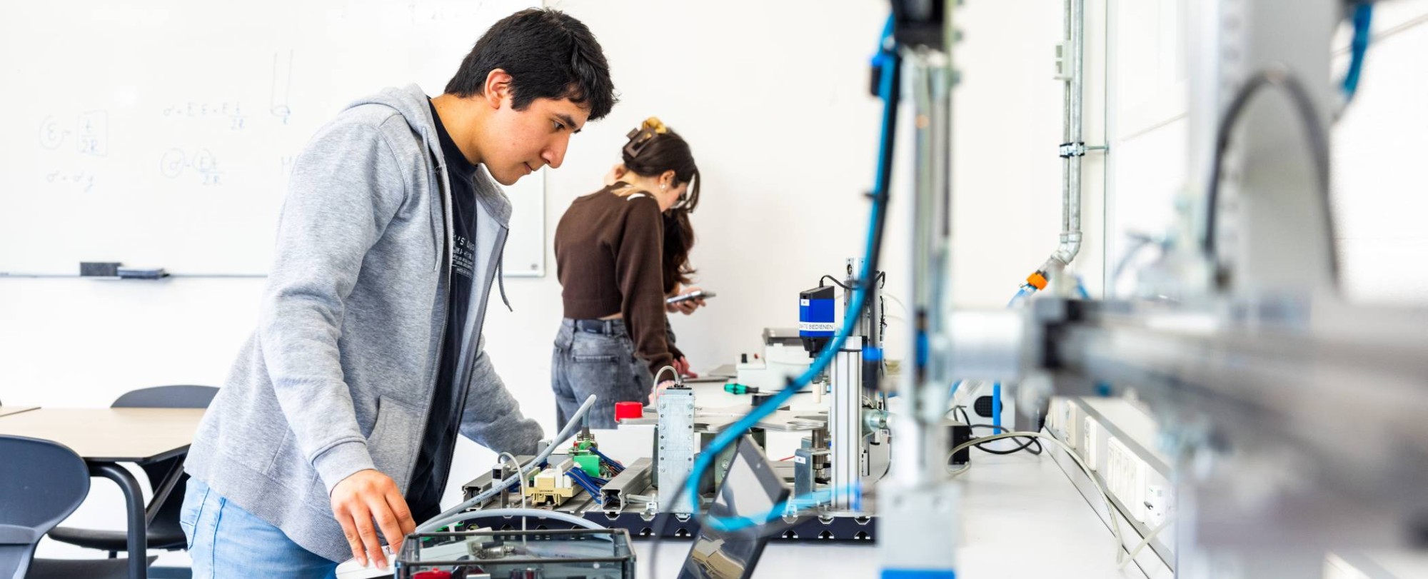 Elektrotechniekstudent Juan werkt aan een PLC in een practicumruimte.