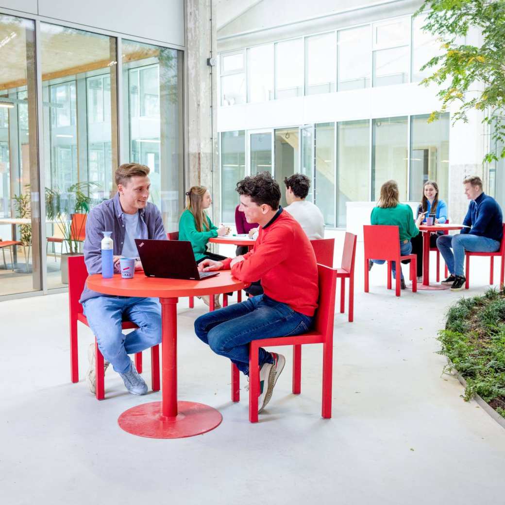 Locatieshot van IPKW met drie groepjes studenten aan tafel. Master Circulaire Economie 2024.