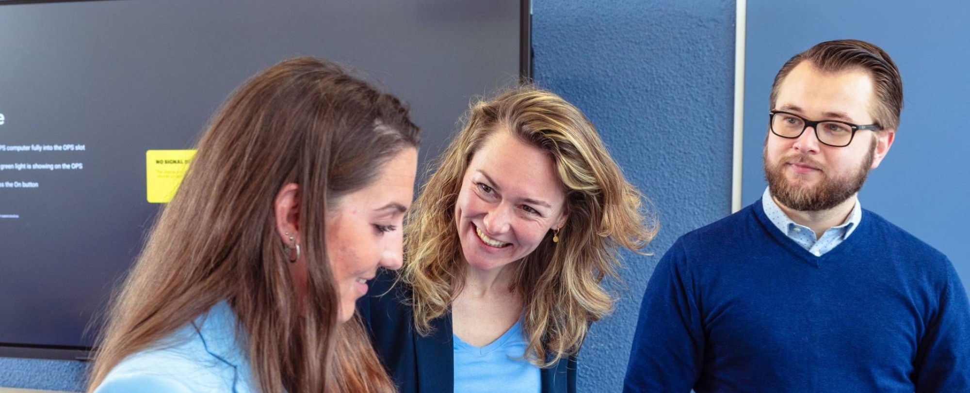 Drie vrouwen zijn aan het overleggen en een van de vrouwen schrijft in een notitieboek