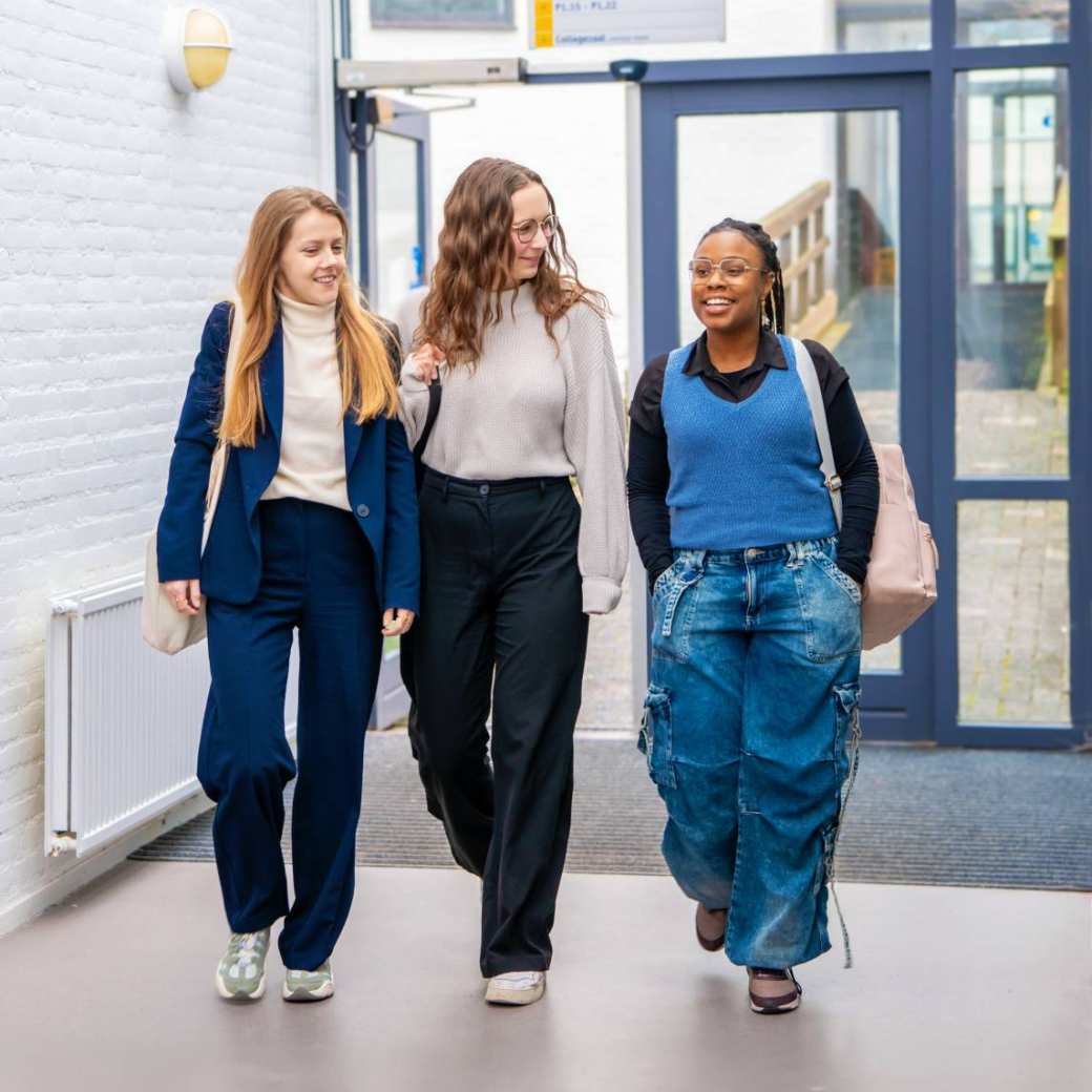 3 vrouwen lopen richting de camera, lachen met elkaar. 