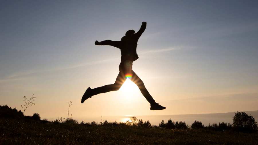 Silhouet van iemand die springt tegen het licht vaneen opkomende zon