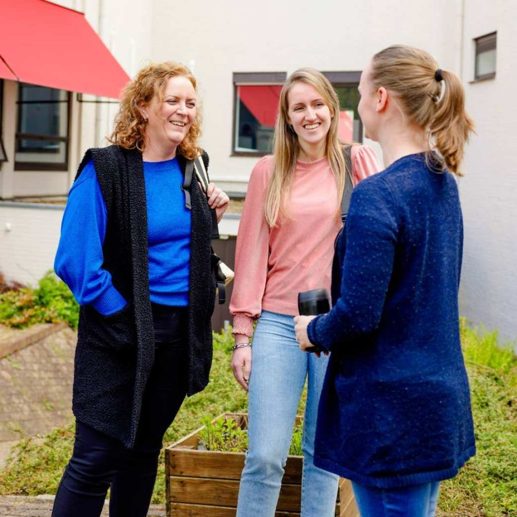 Twee vrouwen staan pratend naast elkaar voor de ingang