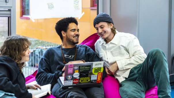 International Social Work. Drie studenten in gesprek. De middelste heeft een laptop. Ze zitten er relaxt bij.